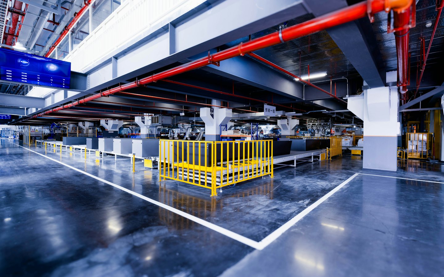 Automated factory assembly line with red pipes and yellow railings.