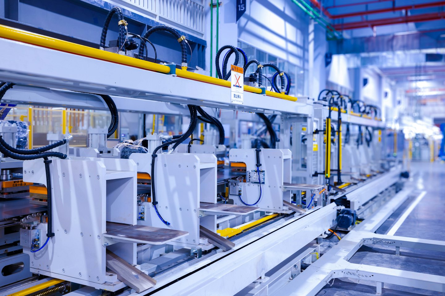 Automated machinery on a factory assembly line with yellow conduits.
