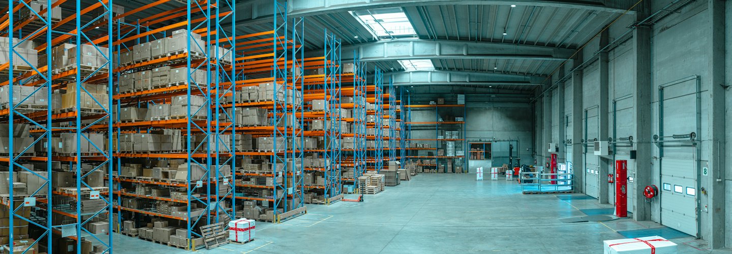 Rows of tall shelves filled with boxes in a large warehouse.