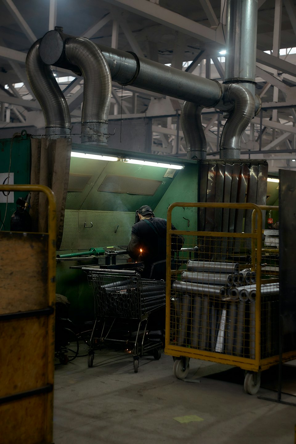 Worker in protective gear welds metal parts in a factory.